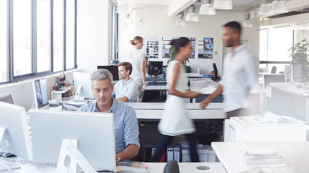 He's getting the job done Shot of a man working at his desk with his colleagues blurred in the backgroundhttp://195.154.178.81/DATA/i_collage/pu/shoots/805874.jpg defocused office business motion stock pictures, royalty-free photos & images