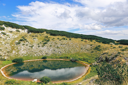 Hiker going behind the lake Crvenjak, Mountain Cvrsnica, Bosnia and Herzegovina