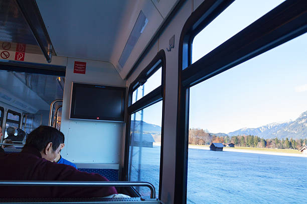 Garmisch-Partenkirchen, Germany - November 21, 2012: Autumn morning in driving Zugspitz train in Bavaria. Two male asian tourists are sitting at window. Landscape is frosty and sunny. Scene is in outskirts of Garmisch-Partenkirchen.