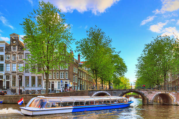 Canal tour bridge Canal cruise boat goes under the bridge over the Leidse canal at the Patricians' or Lords' canal (Herengracht) in Amsterdam in spring jordaan amsterdam stock pictures, royalty-free photos & images