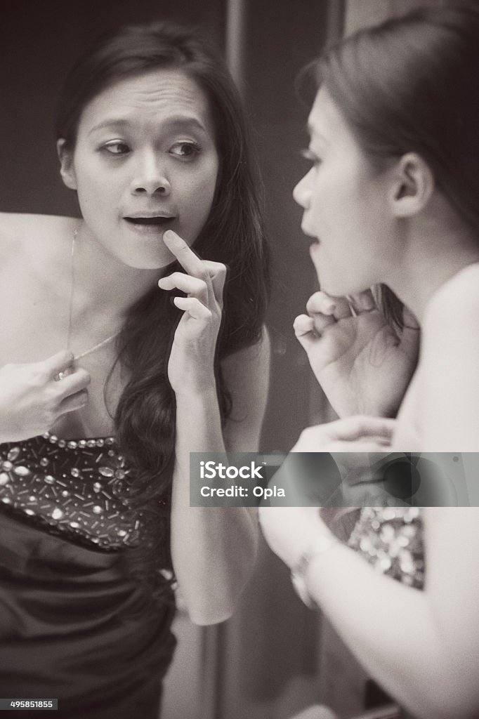 Asian woman in mirror Asian woman checking her make-up in hotel room mirror. Black and white processed.  Asia Stock Photo