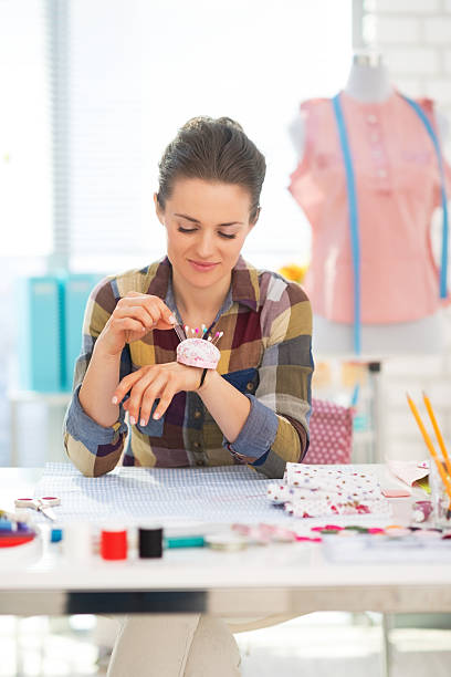 istock seamstress taking needle from pincushion 495852277