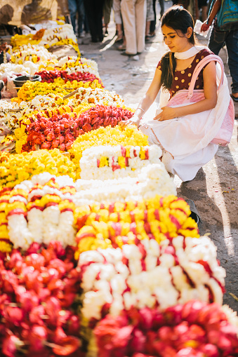A young woman chooses flowers in a busy Jaipur market, India
