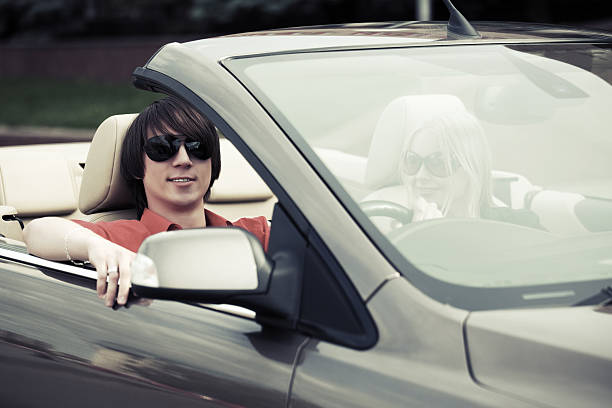 Young couple driving convertible car stock photo