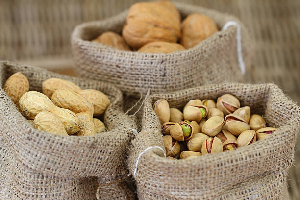 istock Walnuts, pistachio nuts and peanuts in jute bags 495855327