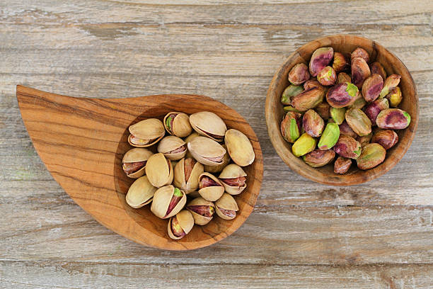 istock Pistachio nuts with and without shell on wooden background 495855463