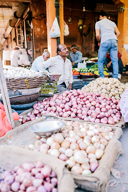Jaipur, India - March 16, 2014: Men in a busy Jaipur market, Rajasthan, India. A stall selling onions is visible in the foreground. 