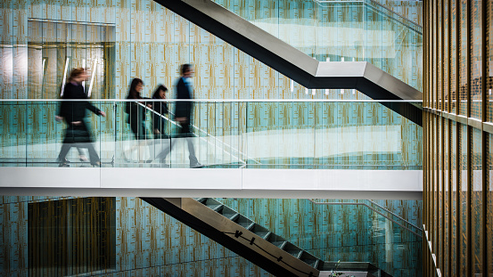 Businessmen and businesswomen walking in office corridor.