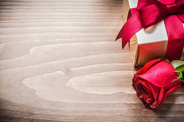 istock Giftbox with tied bow expanded rose on wooden board copyspace 495870568