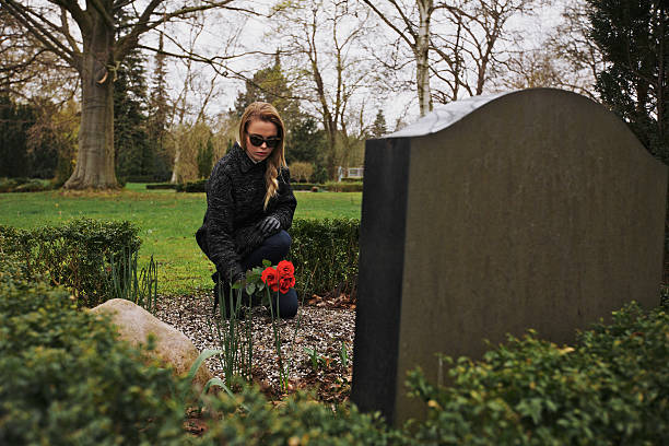 istock Young woman placing roses at a cemetery 495870881