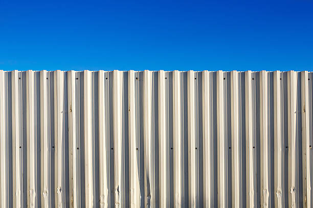 Corrugated white metal fence and blue sky stock photo