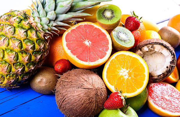istock Pineapple, grapefruit, coconuts, kiwi, orange, bananas, apples on blue plank 495873101