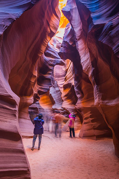 Tourists photographing golden strata of Antelope slot canyon Arizona USA Page, Arizona, USA - November 5, 2013: Tourists photographing the iconic curves of smooth strata and narrow sandy riverbed twisting through Antelope Canyon in Page, Arizona, Southwest USA.  upper antelope canyon stock pictures, royalty-free photos & images