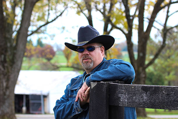 istock Cowboy Leans on Fence While Posing For Camera 495877540