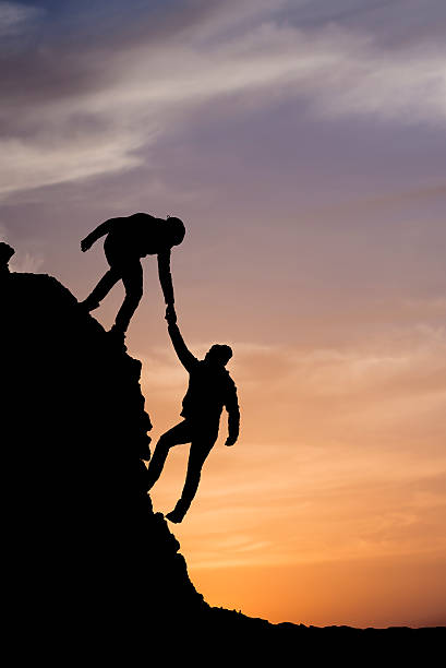silhouette di aiutare mano tra due climber - conquering adversity mountain hiking mountain climbing foto e immagini stock