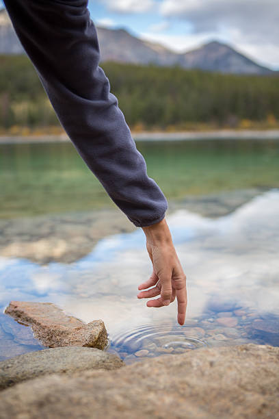 istock Finger touches surface of mountain lake. 495882832