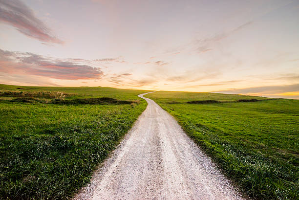 chemin au coucher du soleil - single lane road photos photos et images de collection