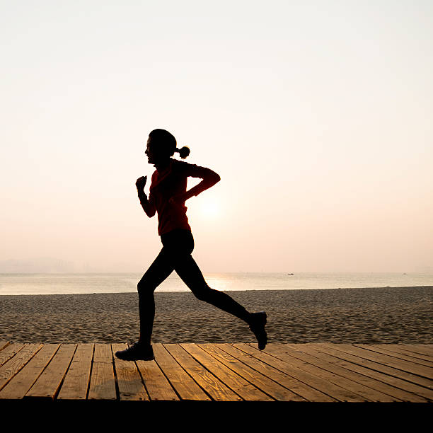 istock Woman jogging on shore at sunrise 495904876