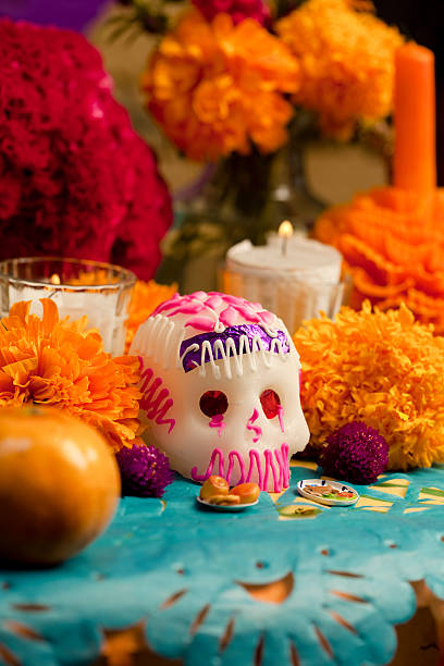 Day of the Dead altar with sugar skull Dia de Muertos (Day of the Dead) altar with traditional decorations: sugar skull, orange cempasùchitl flowers, papel picado (cut tissue paper), fruit and candles. altar stock pictures, royalty-free photos & images