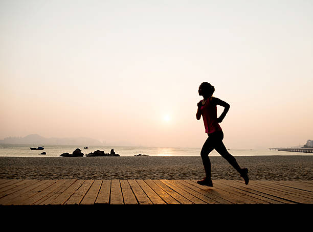 istock Woman jogging on shore at sunrise 495907196