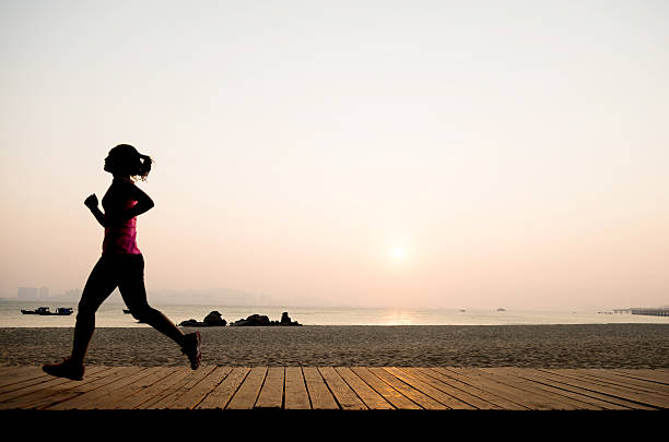 istock Woman jogging on shore at sunrise 495907270