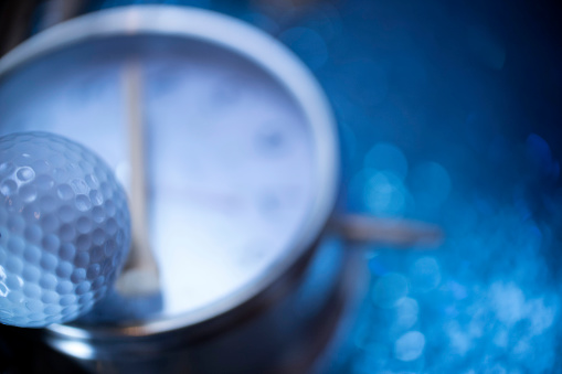 close up shot of golf ball and a clock