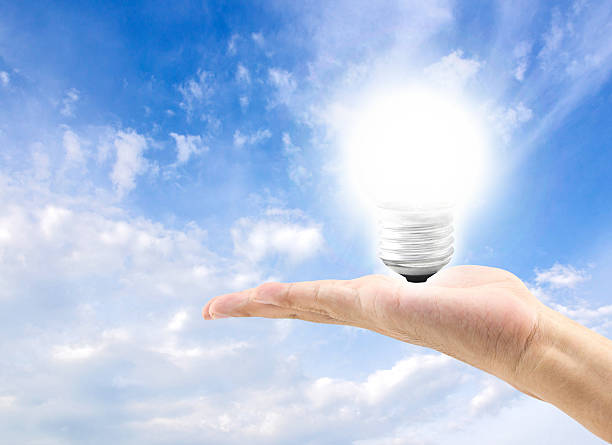 istock Energy efficient bulb in hand with blue sky in background 495911098