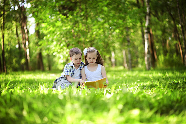 istock Children reading a book in the summer park 495916251