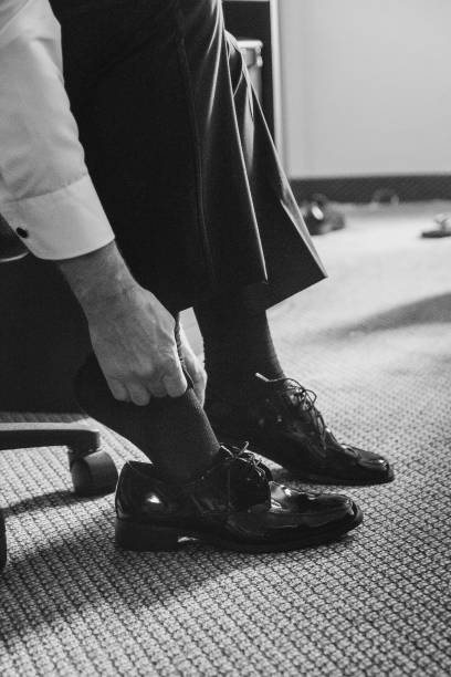 istock Man putting on shiny formal dress shoes 495923440