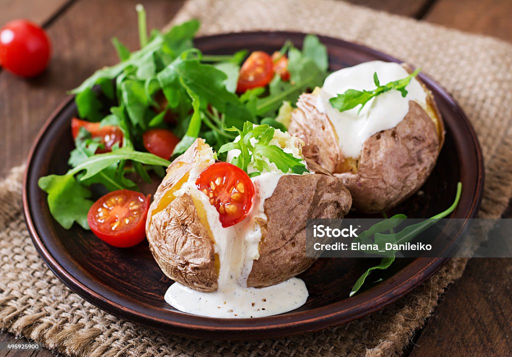 Baked potato filled with sour cream, arugula and tomatoes 2015 Stock Photo