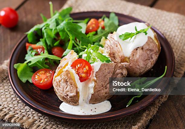 Baked Potato Filled With Sour Cream Arugula And Tomatoes Stock Photo - Download Image Now