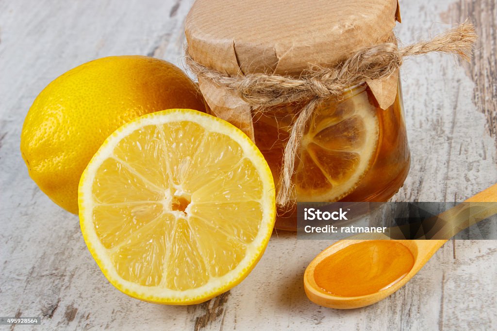 Fresh lemon and honey on wooden table, healthy nutrition Glass jar with lemon and honey, fresh lemon and honey on wooden spoon lying on old wooden white table, healthy food and strengthening immunity 2015 Stock Photo