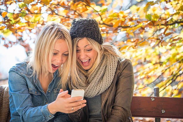 istock Friends using smartphone in autumn outdoor park 495932384