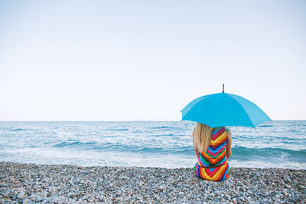 femme séance avec jets de relaxation et d'un parasol près de la mer - rain women umbrella parasol photos et images de collection