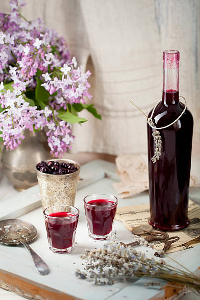 Blackcurrant homemade liquor with lilac flowers. Wooden background Blackcurrant homemade liquor on a wooden background with lilac flowers casis stock pictures, royalty-free photos & images