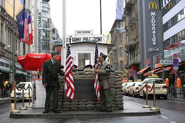 Checkpoint Charlie Berlin, Germany - April 27, 2015: Checkpoint Charlie ("Checkpoint C") was the name given by the Western Allies to the best-known Berlin Wall crossing point between East Berlin and West Berlin during the Cold War. Today it`s a one of Berlin's primary tourist attractions. Tourists can have their photographs taken for a fee with actors dressed as allied military policemen standing in front of the guard house soldier on the wall stock pictures, royalty-free photos & images