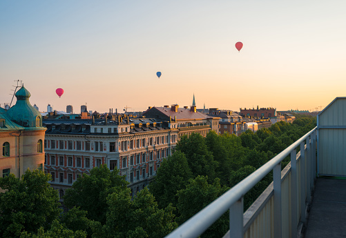 Sunset from penthouse terrace over lush esplanade in Stockholm with hot air balloons in the background