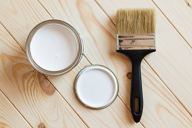 Cans of paint and brush on wooden background stock photo