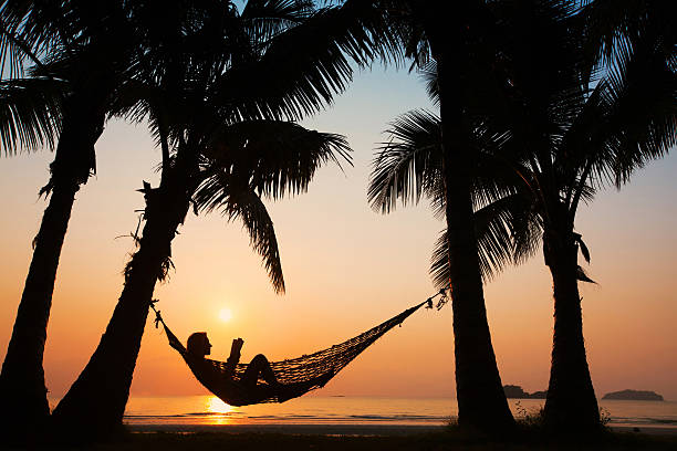 beach vacations, silhouette of woman reading in hammock