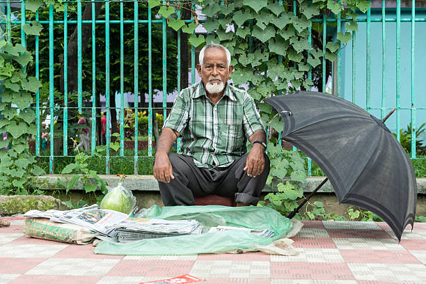 Paper Delivery Person Dhaka, Bangladesh - August 8, 2014 : a old people is at the street to sell newspaper at Dhaka, Bangladesh. newspaper seller stock pictures, royalty-free photos & images