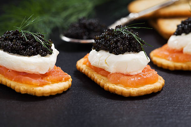istock Black caviar served on crackers with salmon and cream cheese. 495976896
