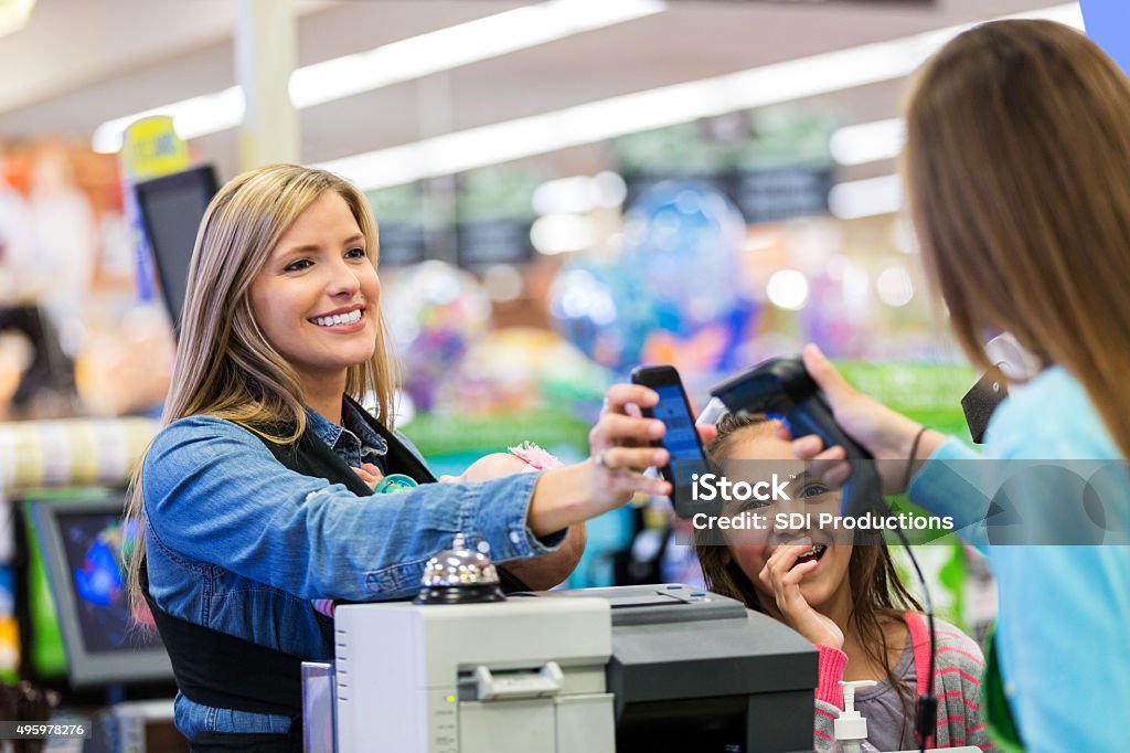 Mère à payer pour vos courses avec le téléphone intelligent application en magasin - Photo de Client libre de droits