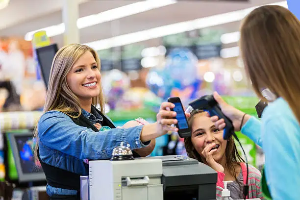 Photo of Mother paying for groceries with smart phone app in store