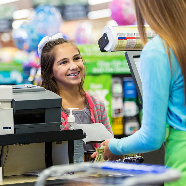 istock Elementary age girl paying for something at grocery store 495978328