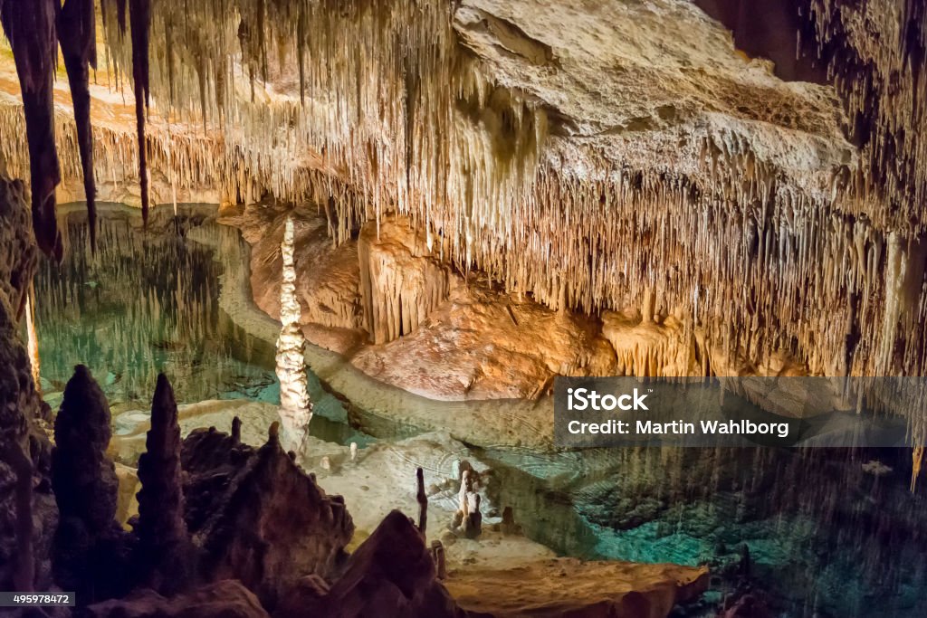 Inside a big limestone cave with an underground lake Inside a big limestone cave with an underground sea water lake. This is Cuevas del Drach in Mallorca, Spain. Stalactite Stock Photo