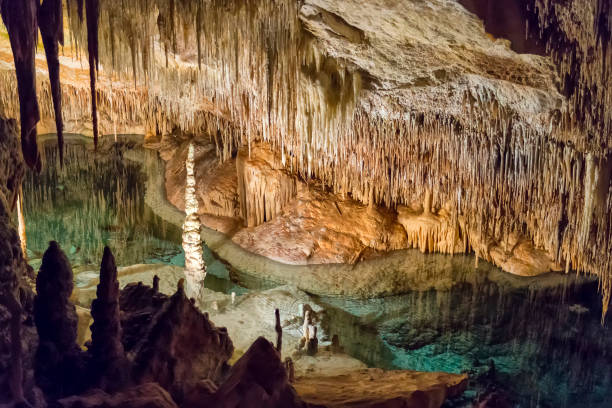 Inside a big limestone cave with an underground lake Inside a big limestone cave with an underground sea water lake. This is Cuevas del Drach in Mallorca, Spain. stalactite stock pictures, royalty-free photos & images