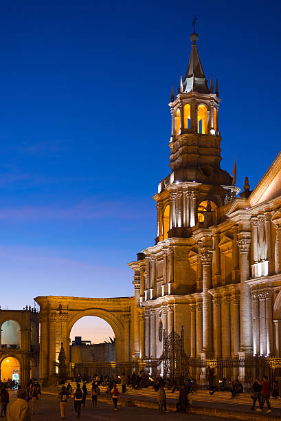 Arequipa, Peru - August 15, 2015: People on the main square, Plaza de Armas, of Arequipa, famous travel destination and landmark in Peru. Details of the majestic Cathedral glowing in the night.