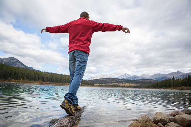 istock Man walking on a tree log on the lake 495989534