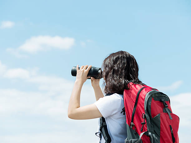 istock Female hiker looking through binoculars on top 495991288