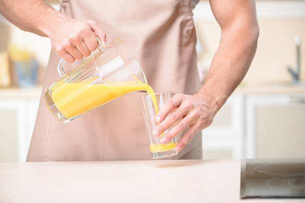 istock Young male kitchen worker pouring orange juice 496024936